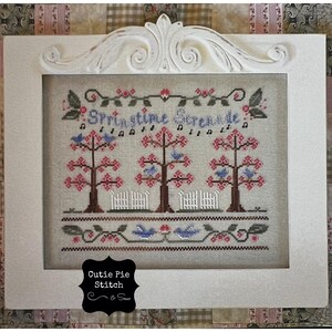 May include: A framed cross-stitch embroidery with the text "Springtime Serenade" and a design of three trees with pink blossoms and blue birds. The embroidery is signed "Cutie Pie Stitch & Sew".