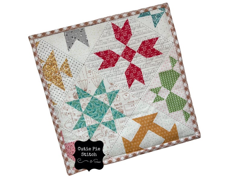 May include: A square, quilted patchwork featuring various geometric shapes in red, teal, gold, and green on a white background. The quilt has a brown and white checkered border and the text "Cutie Pie Stitch & Sew".