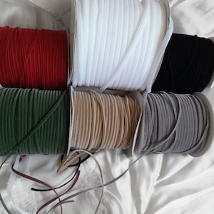 May include: Spools of velvet ribbon in red, green, beige, gray, white, and black.