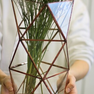 May include: A geometric glass vase with a copper frame, holding a bouquet of dried lavender flowers. The vase is clear and has a modern design.