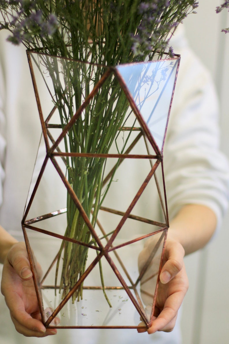 May include: A geometric glass vase with a copper frame, holding a bouquet of dried lavender flowers. The vase is clear and has a modern design.