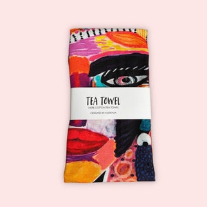 Pu&ograve; includere: Un asciugamano da t&egrave; colorato con un design di viso astratto. L'asciugamano &egrave; in 100% cotone e progettato in Australia. Il testo "TEA TOWEL 100% COTTON TEA TOWEL DESIGNED IN AUSTRALIA" &egrave; stampato su un'etichetta bianca.