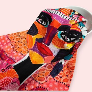 Pu&ograve; includere: Un viso astratto colorato stampato su un tessuto rosa e arancione con sfondo nero. Il tessuto ha un motivo a pois.