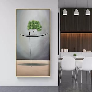 Op de afbeelding: Een verticaal rechthoekig wandkunstwerk in een gouden lijst met een surrealistische scène van een kleine zwarte boot die in een grijze lucht zweeft. Een enkele groene boom groeit uit de boot en een dunne zwarte lijn loopt naar de beige ondergrond.