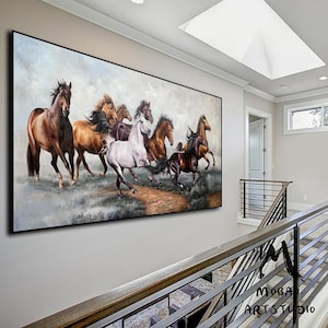 Op de afbeelding: Een groot rechthoekig wandkunstwerk met een dynamisch olieverfschilderij van een kudde paarden die over een veld galoppeert. De scène toont bruine, witte en zwarte paarden in beweging tegen een bewolkte lucht met aardse tinten en texturen.