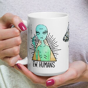 May include: White ceramic mug with a green alien smoking a cigarette inside a triangle with the text "EW, HUMANS".