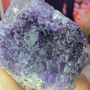 May include: A large, purple fluorite crystal with a cluster of smaller crystals. The crystal has a sparkly, iridescent surface.