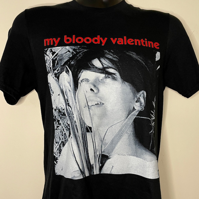 May include: Black t-shirt with a white and gray photo of a woman's face and the text "my bloody valentine" in red.