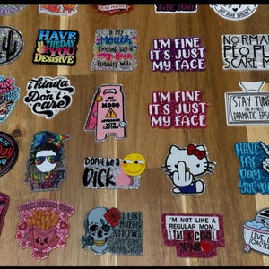 May include: A collection of colorful, glittery, and humorous stickers with various sayings. The stickers feature a variety of designs, including cartoon characters, skulls, and text-based designs. The stickers are perfect for adding a touch of personality to laptops, water bottles, or other surfaces.