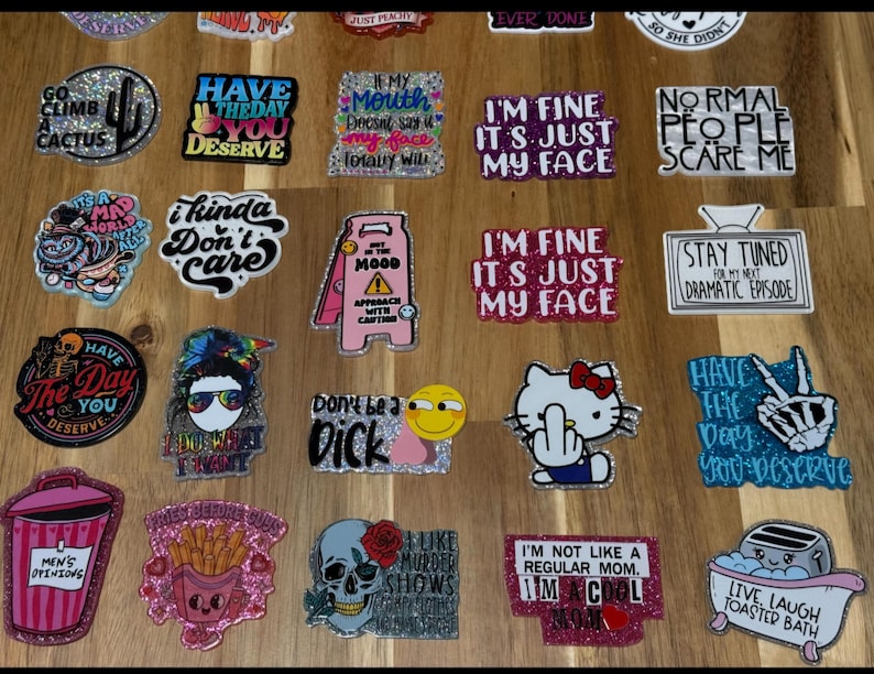 May include: A collection of colorful, glittery, and humorous stickers with various sayings. The stickers feature a variety of designs, including cartoon characters, skulls, and text-based designs. The stickers are perfect for adding a touch of personality to laptops, water bottles, or other surfaces.