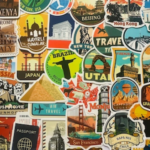 Puede incluir: Una colección de pegatinas de viaje coloridas con monumentos y destinos icónicos. Las pegatinas incluyen la Torre Eiffel, la Estatua de la Libertad, el Golden Gate y la Torre de Pisa. Las pegatinas son de varias formas y tamaños.