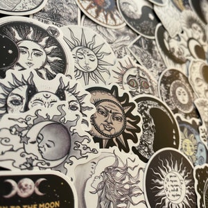May include: A collection of black and white sun and moon stickers with various designs. The stickers feature detailed illustrations of celestial bodies, including faces and intricate patterns.