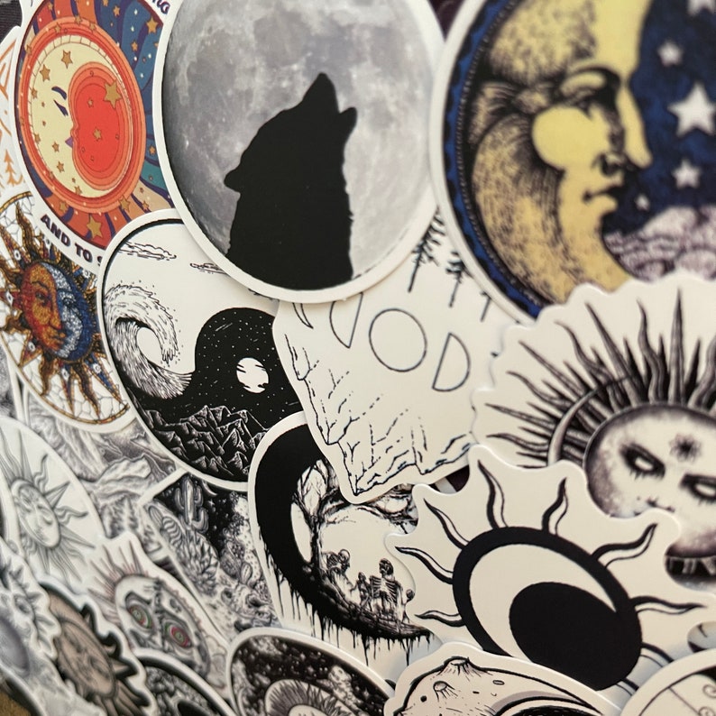 May include: A collection of black and white stickers with various designs, including a wolf howling at the moon, a yin yang symbol, a tree with branches, and a sun with a face. The stickers are on a white background.