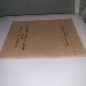 May include: A tan-coloured folder with the text "Historical Materials in the Harry S. Truman Library Truman Centennial Edition 1884-1984" printed on the front.