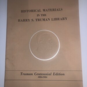 May include: A tan-coloured booklet with the title "Historical Materials in the Harry S. Truman Library" and the text "Truman Centennial Edition 1884-1984". A circular image of Harry S. Truman is in the centre of the booklet.