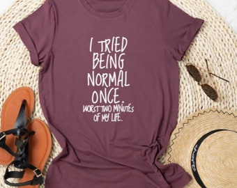Op de afbeelding: Een maronkleurig T-shirt met witte tekst die luidt: "Ik heb geprobeerd normaal te zijn. De slechtste twee minuten van mijn leven."