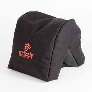 May include: Black fabric camera beanbag with a red paw print logo that says "grizzly the wild shoulder bag.com".