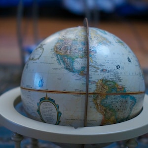 May include: A white globe with a detailed map of the world. The globe is on a white stand with a wooden base.