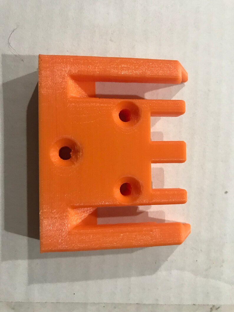 May include: Orange plastic 3D printed part with three slots and three holes.
