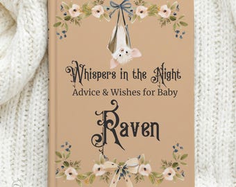May include: A tan hardcover book titled Whispers in the Night Advice & Wishes for Baby Raven. The cover features a hanging bat illustration, floral garlands at the top and bottom, and a decorative bow at the bottom center in dark blue and pink.