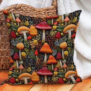 Faux embroidered mushroom pillow covers. Mushrooms are red, orange, and yellow on a black background. They are surrounded by ferns and berries.