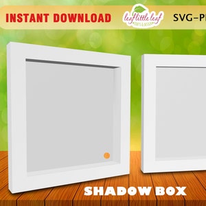 Puede incluir: Dos cajas de sombra blancas con un borde elevado alrededor de los bordes. Las cajas están sobre una superficie de madera.