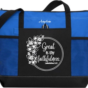 May include: A blue and black tote bag with a white floral design and the text "Great is thy faithfulness. Lamentations 3:23". The bag has a zippered pocket and a mesh pocket on the side. The name "Angelina" is embroidered on the top of the bag.