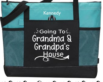 Peut inclure: Un sac fourre-tout bleu sarcelle et noir avec le texte blanc Kennedy et Going To Grandma & Grandpa's House. Le sac comprend des poignées noires, une grande poche avant et des poches latérales en filet. Une rangée de sacs est visible.