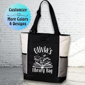 May include: Black and white tote bag with the text "Olivia's Library Bag" and a stylized image of an open book with flowers and a crescent moon.