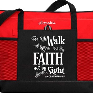 Op de afbeelding: Rode en zwarte tote bag met een ritssluiting en mesh-zakken. De tas heeft een wit ontwerp met de tekst "For We Walk by Faith not by Sight 2 Corinthians 5:7".