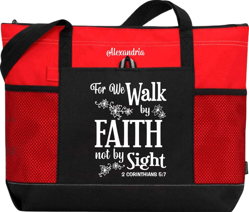 Op de afbeelding: Rode en zwarte tote bag met een ritssluiting en mesh-zakken. De tas heeft een wit ontwerp met de tekst "For We Walk by Faith not by Sight 2 Corinthians 5:7".