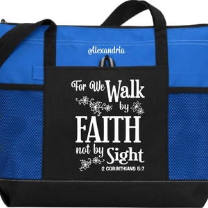 Op de afbeelding: Een blauwe en zwarte tote bag met een wit ontwerp dat "For We Walk by Faith not by Sight 2 Corinthians 5:7" zegt. De tas heeft een mesh-zak aan de zijkant en een ritszak aan de voorkant.