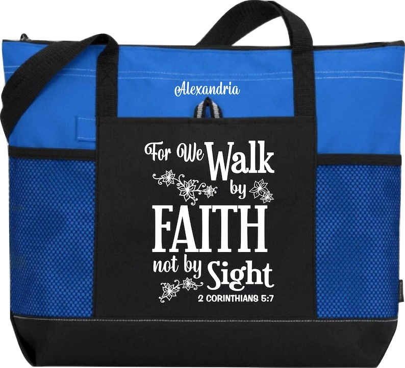 Op de afbeelding: Een blauwe en zwarte tote bag met een wit ontwerp dat "For We Walk by Faith not by Sight 2 Corinthians 5:7" zegt. De tas heeft een mesh-zak aan de zijkant en een ritszak aan de voorkant.