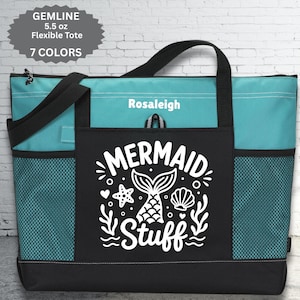 May include: A teal and black tote bag with the words "Mermaid Stuff" in white script. The bag has a mermaid tail graphic and side mesh pockets. The bag also has the name "Rosaleigh" printed on it.