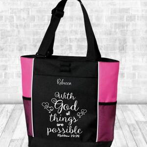 May include: Black and pink tote bag with a black handle and side pockets. The bag features the name "Rebecca" and the text "With God all things are possible Matthew 19:26" in white script.