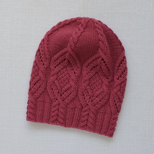 May include: A burgundy knitted hat with a cable knit pattern.