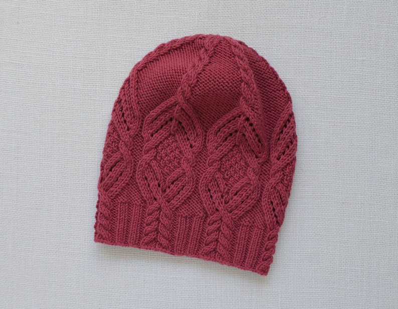 May include: A burgundy knitted hat with a cable knit pattern.