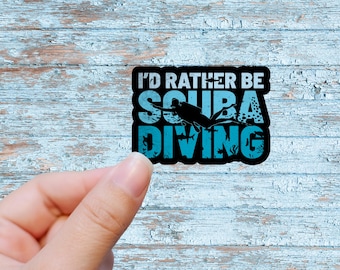 May include: A black and blue sticker with the text "I'd rather be scuba diving". The sticker features a silhouette of a scuba diver with a diving tank and fins.