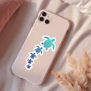 May include: A white phone case with a sticker of a line of blue and green sea turtles. The turtles are different sizes and are arranged in a line from largest to smallest.