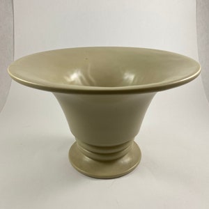 May include: A light beige ceramic vase with a wide, flared opening and a round base with a raised, textured band.