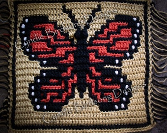 Puede incluir: Cuadrado tejido a crochet con un diseño de mariposa negra y roja con detalles blancos. El cuadrado está enmarcado con un borde marrón y tiene flecos en todos los lados. El texto "Cyndie Birdsong Designs" es visible en la imagen.