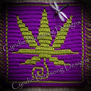 May include: A crocheted square with a green marijuana leaf design on a purple background. The square has fringe on all four sides. The text "Cynide Birdsong Designs" is visible in the image.