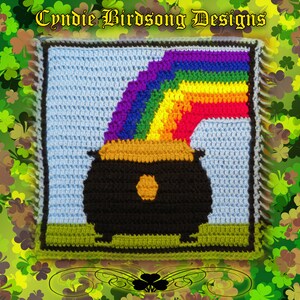 Peut inclure: Un carré crocheté représentant un pot d'or au bout d'un arc-en-ciel. Le pot d'or est noir avec un bord doré et une pièce d'or à l'intérieur. L'arc-en-ciel est fait de fils de différentes couleurs, dont le rouge, l'orange, le jaune, le vert, le bleu, l'indigo et le violet. L'arrière-plan est de couleur bleu clair, et le pot d'or est posé sur une touffe d'herbe verte.