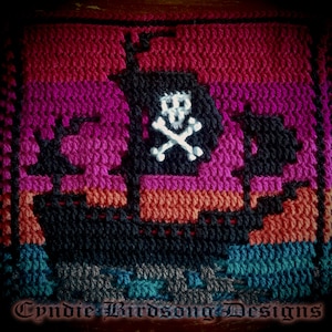 May include: A crocheted pirate ship with a skull and crossbones design. The ship is made with different colored yarn, including red, pink, orange, black, and blue.