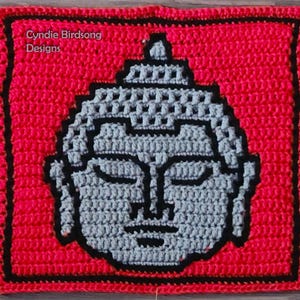 May include: A crocheted square with a gray Buddha face in the center. The square is surrounded by a black border and a red background. The text "Cynie Birdsong Designs" is in the top left corner.