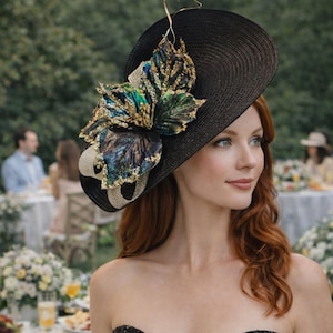 Könnte beinhalten: Ein schwarzer Hut mit breiter Krempe und dekorativem Blumenschmuck. Der Hut hat ein großes, verziertes Ornament mit goldenen, teal- und blauen Akzenten. Ein stilvolles Accessoire, geeignet für besondere Anlässe.