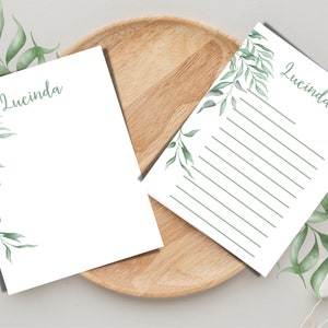 May include: Two blank stationery note cards with a green watercolor leaf design and the name "Lucinda" printed on each card.
