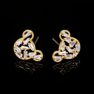 K&ouml;nnte beinhalten: Ein Paar goldfarbene Ohrringe mit einem Mickey-Maus-Silhouetten-Design. Die Ohrringe sind mit klaren Zirkonia-Steinen verziert.