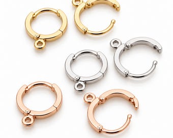 May include: A collection of six circular metal earring findings in gold, silver, and rose gold tones. Each piece features a hinged hoop design with a small integrated loop at the base for attaching charms or dangles, presented in a set.