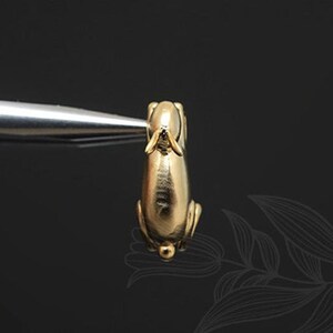 Puede incluir: Una figurita de conejo de color dorado con un acabado liso y brillante. El conejo est&aacute; de pie sobre sus patas traseras con las patas delanteras levantadas.